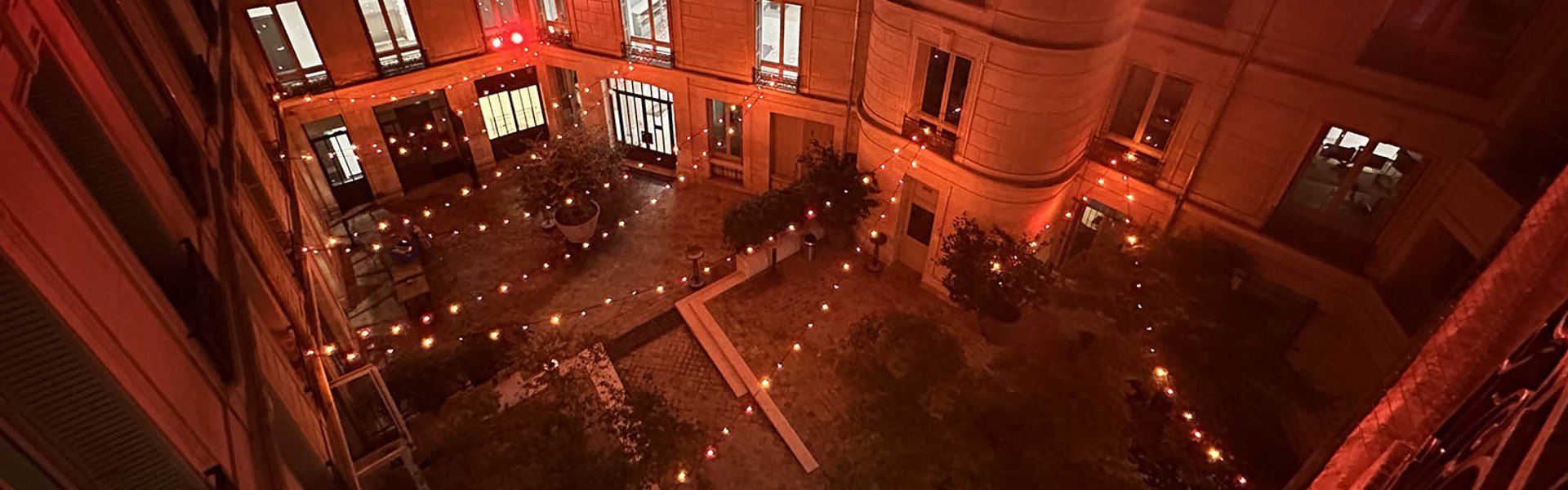 Vue en hauteur d’une cour illuminée par des guirlandes rouges et orangées